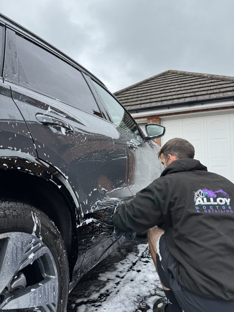 Male in Alloy Doctor and Detailing uniform cleaning a car
